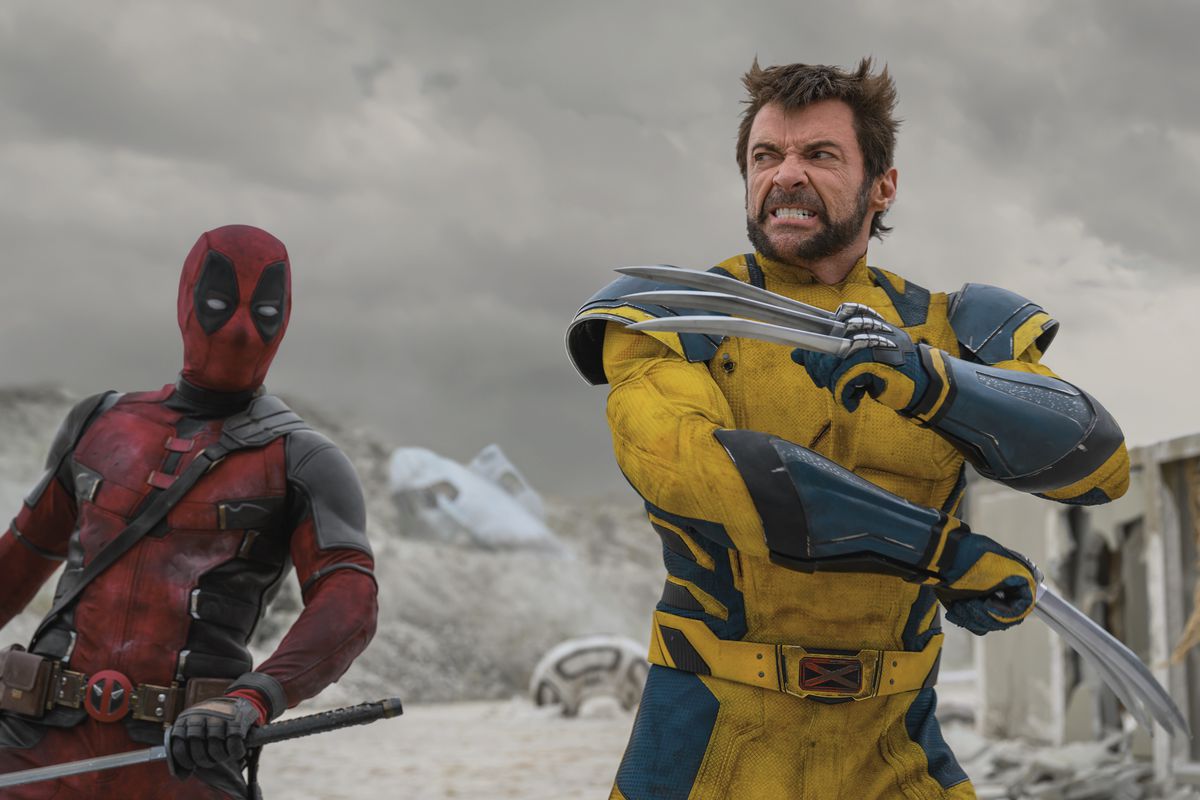 Wolverine pops his claws with his arms across his chest as Deadpool looks on sword in hand in a scene from Deadpool &amp; Wolverine