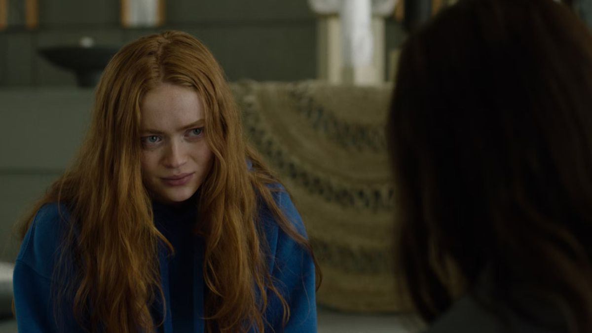 A young woman with long red hair stares across a table at another woman with long dark hair in A Sacrifice.