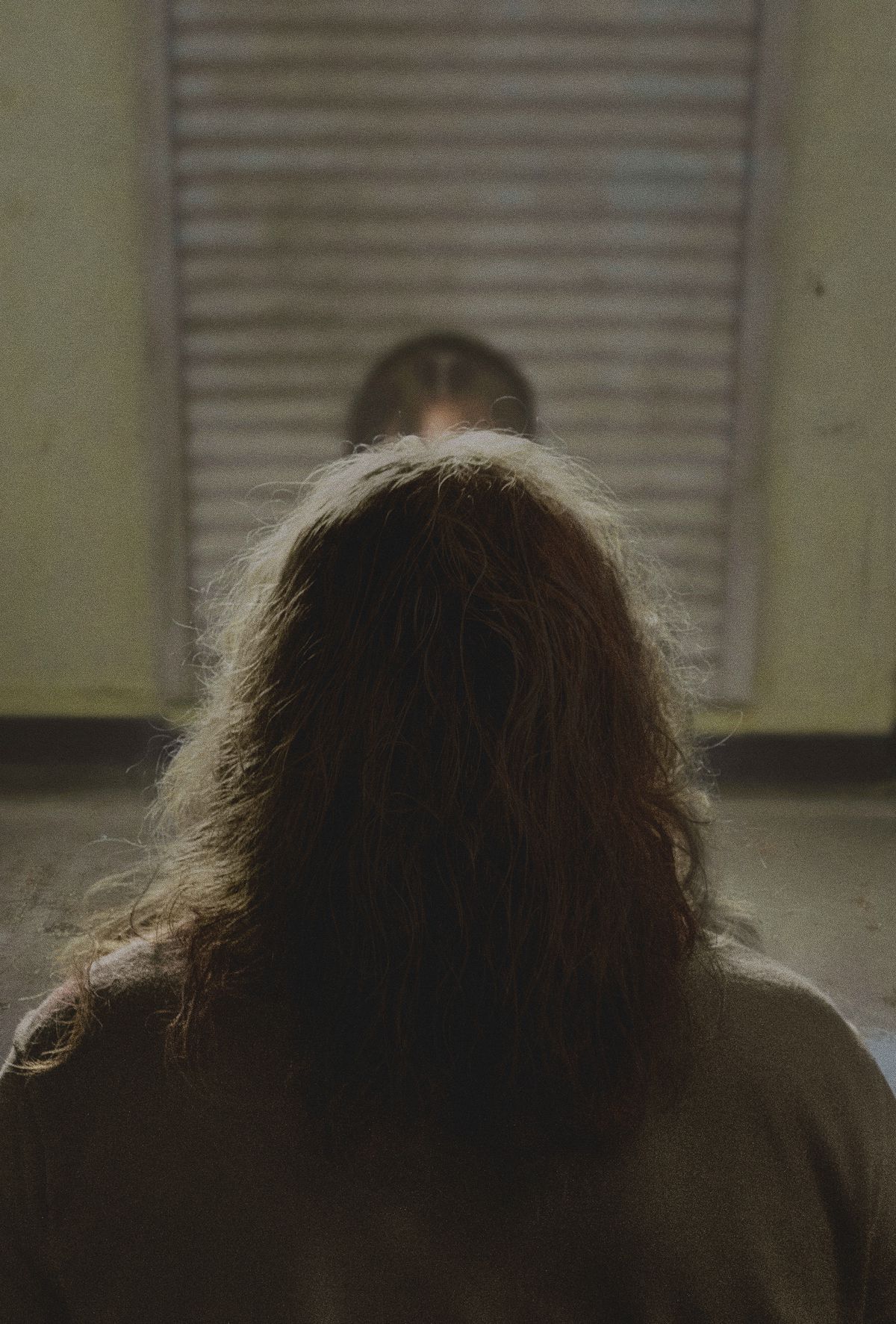 The back of Nicolas Cage’s head in Longlegs, as he sits at an metal table in an interrogation room