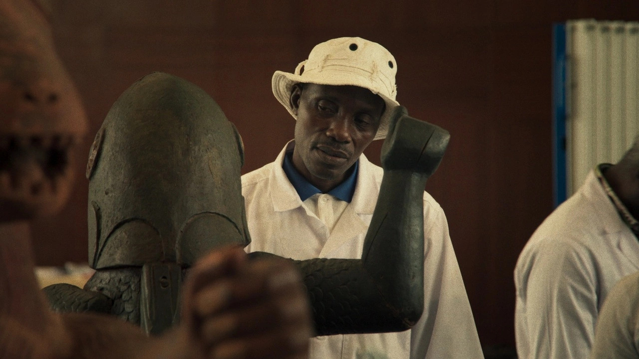 A man wearing a white hat and suit staring at a statue in a museum gallery in Dahomey