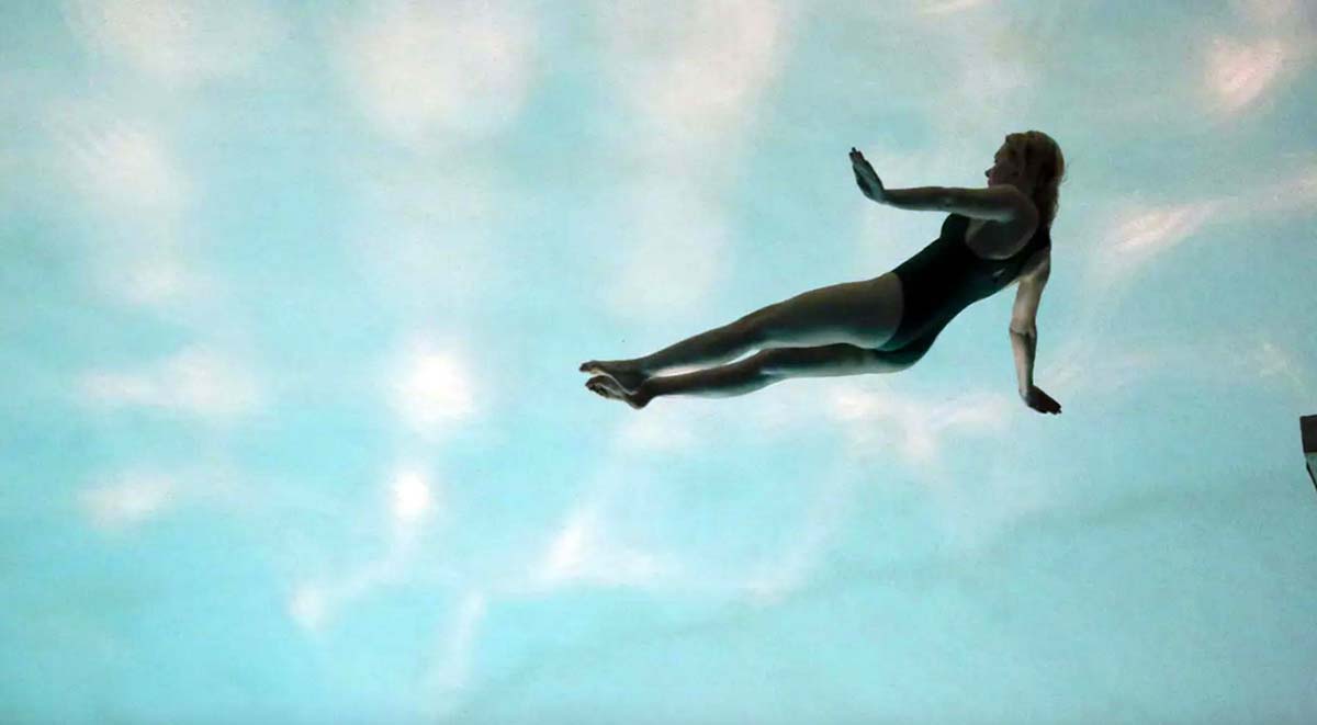 A women in a bathing suit suspended above a pool of water in It’s Not Me.