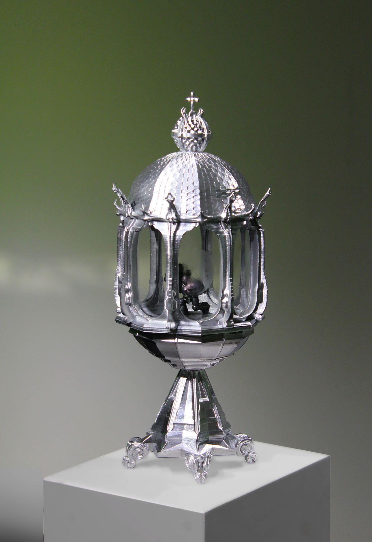 An ornate silver reliquary containing a Warhammer 40,000 Space Marine figurine in a kneeling position