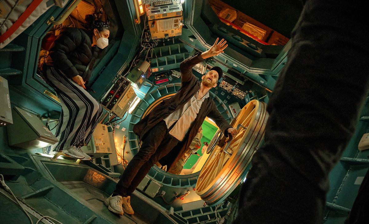 Director Johan Renck stands on the set of Spaceman, in a colorful spaceship capsule, reaching for something above his head