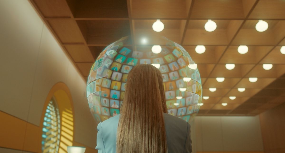 Lindy, a blonde woman shot from behind, her face entirely surrounded by a globe of screens with faces on it, like an enormous Zoom call, in the Doctor Who episode “Dot and Bubble.”