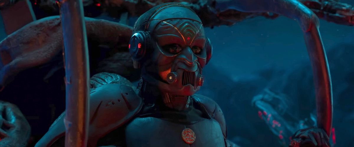 in a promo still for the Indian sci-fi blockbuster Kalki 2898 AD, a humanoid figure in metal armor and mask sits in a dark space, surrounded by metal spars