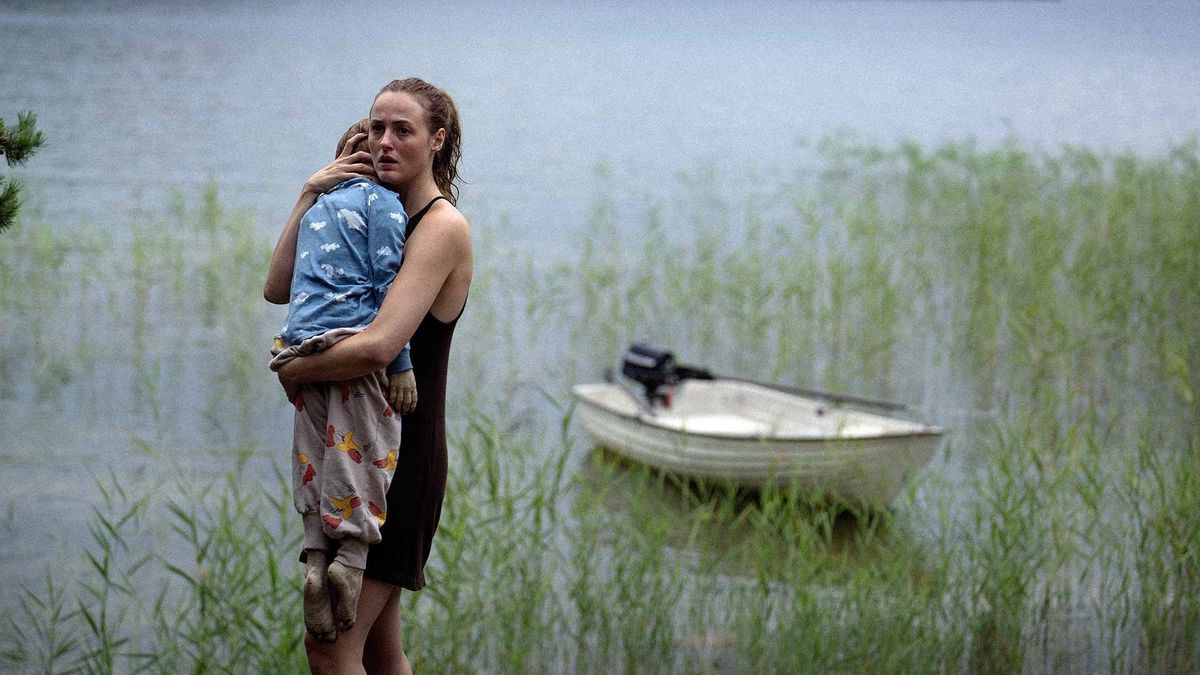 A woman holding the limp body of child in her arms beside a boat surrounded by marsh of reeds in Handling the Undead.