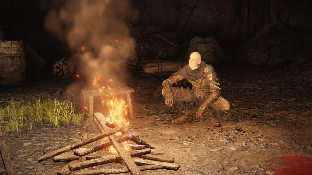 Patches squats near a small campfire in Murkwater Cave in a screenshot from Elden Ring